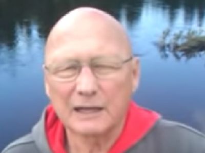 James Tolkan is sitting next to a lake.
